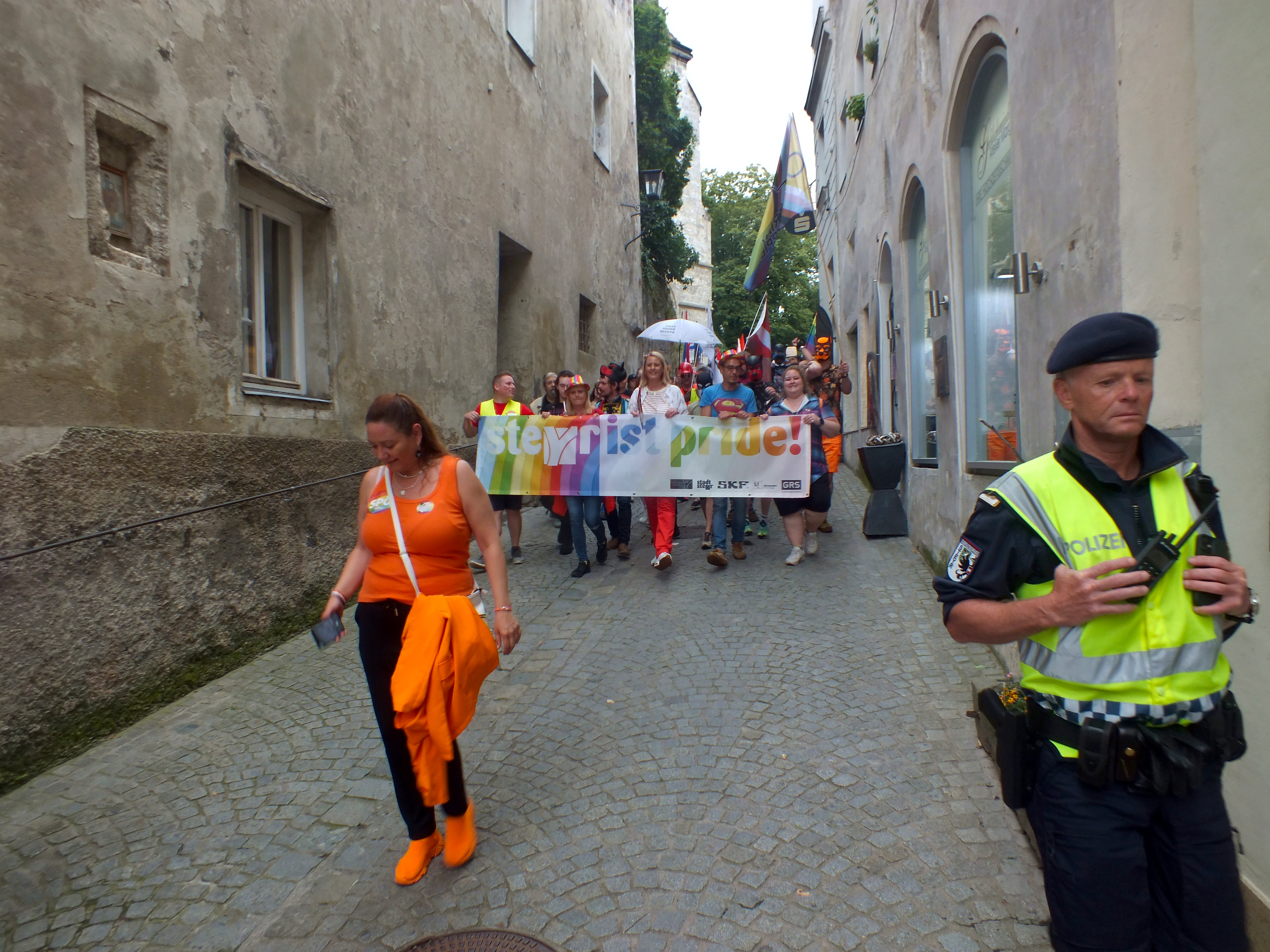 Uczestnicy marszu równości z tęczowymi flagami na ulicy podczas Steyr Pride 2024