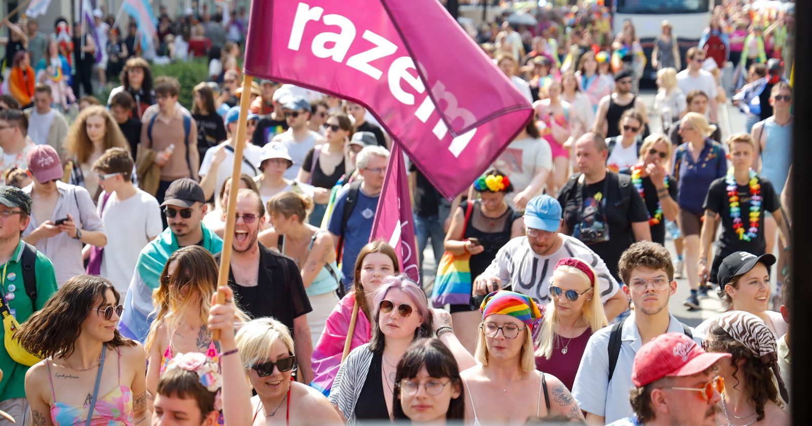 Tłum uczestników Marszu Równości na ulicy polskiego miasta, z dużą flagą Partii Razem i flagami transpłciowymi